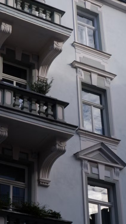 Fassade eines Altbau-Mehrfamilienhauses mit Balkonen und Stuckfenstern